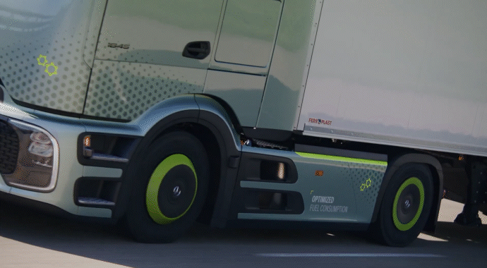 Ein hellgrüner Mercedes-Benz LKW mit einem weißen Auflieger fährt schnell auf einer Landstraße.