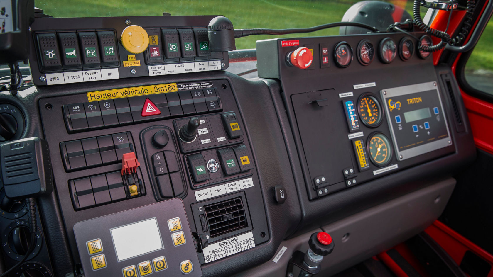Das Cockpit eines Mercedes-Benz-Fahrzeugs mit verschiedenen Bedienelementen, Schaltern und Anzeigen für Steuerung und Überwachung. Kontrastreiche Tasten und Instrumente sind sichtbar.
