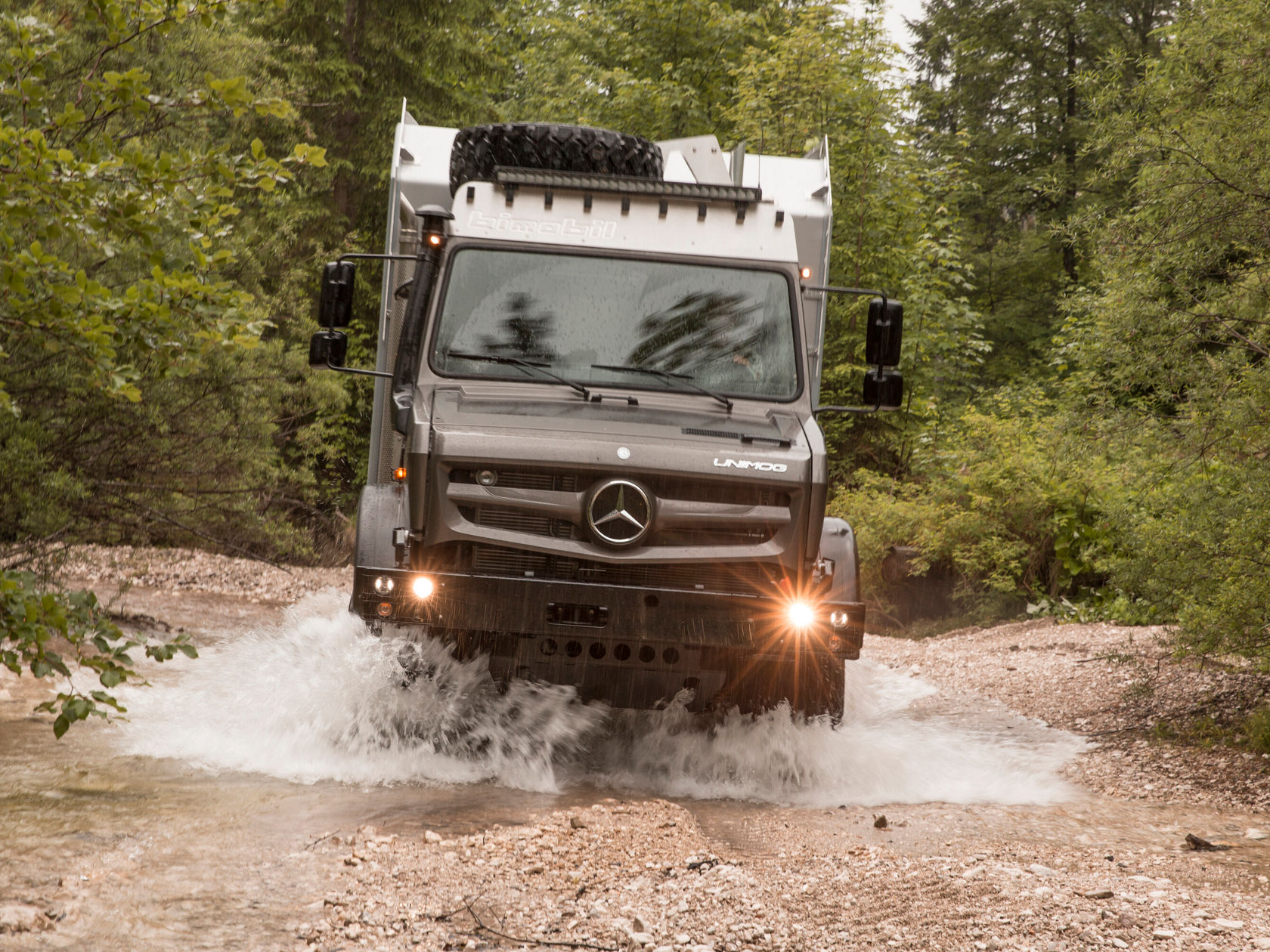 Von Bimobil ausgestatteter Unimog durchfährt einen Fluss.