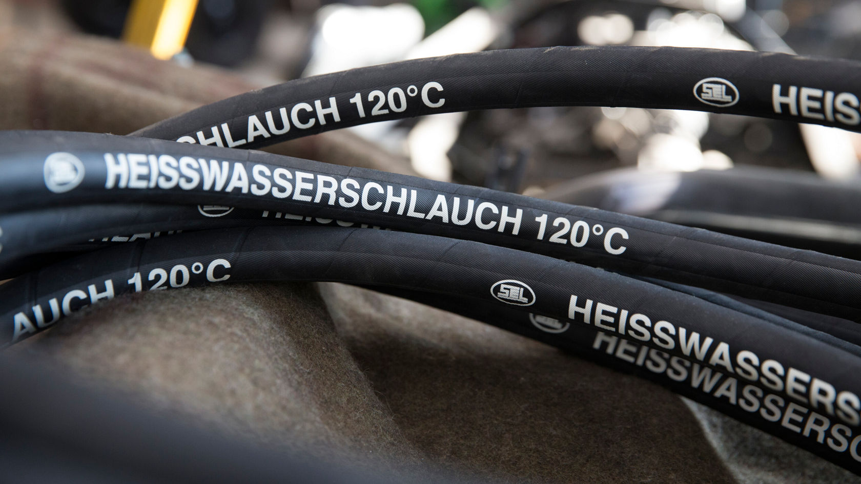 Schwarze Schläuche mit der Aufschrift „HEISSWASSERSCHLAUCH 120°C“ sind zu sehen.