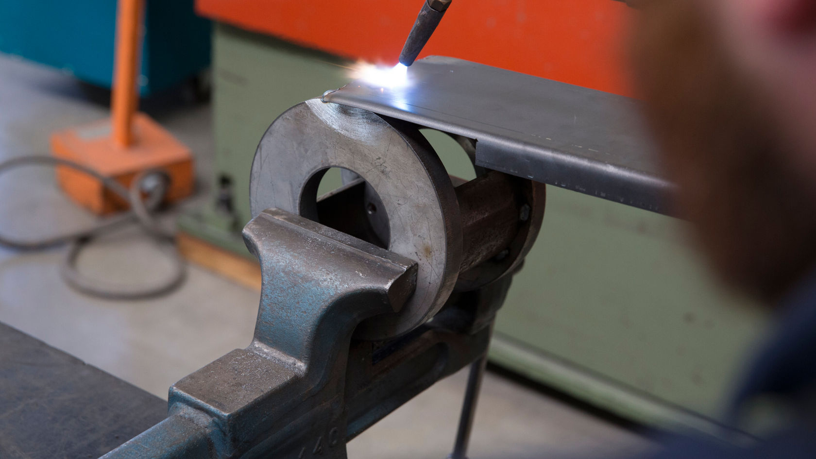 Eine Metallplatte wird in einer Werkbank gehalten.