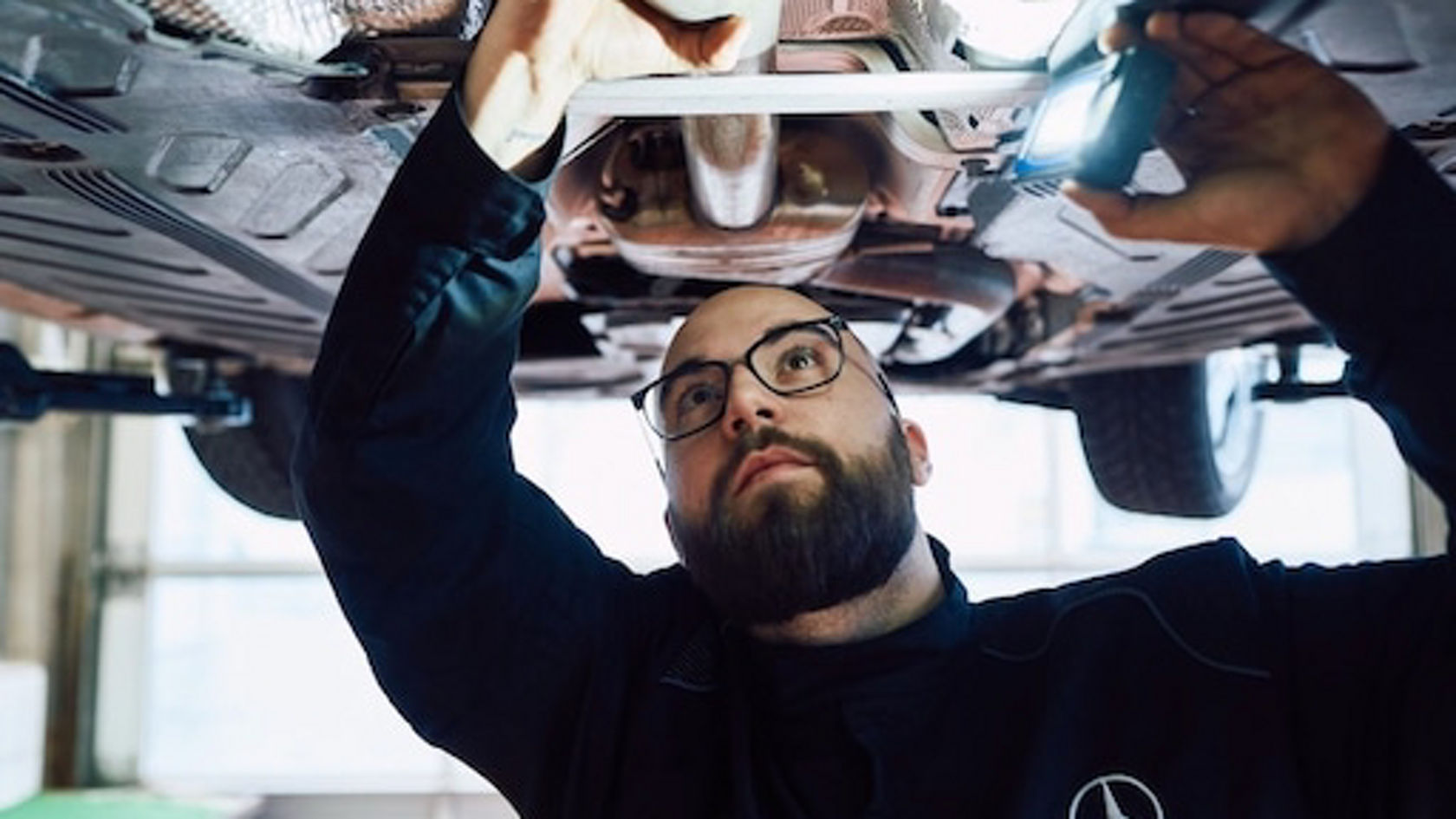 Mechaniker unter einem Fahrzeug in der Werkstatt