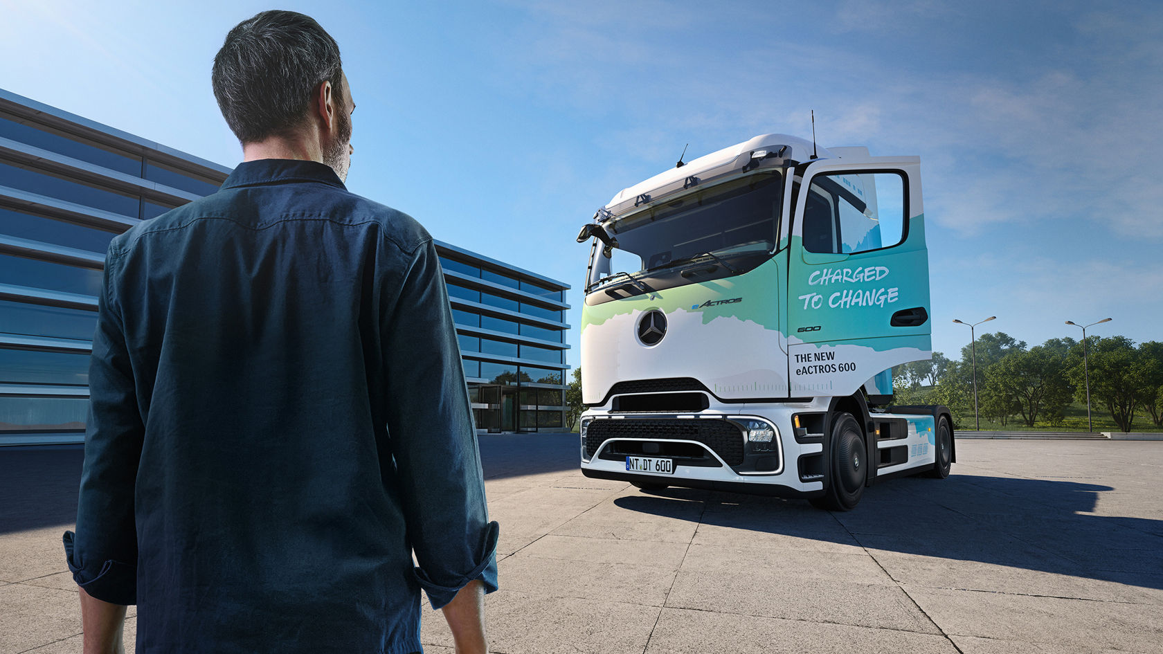 Ein Mann steht vor einem weißen, elektrischen Mercedes-Benz LKW. Die Fahrertür des LKW ist geöffnet und lädt zum Einsteigen ein.