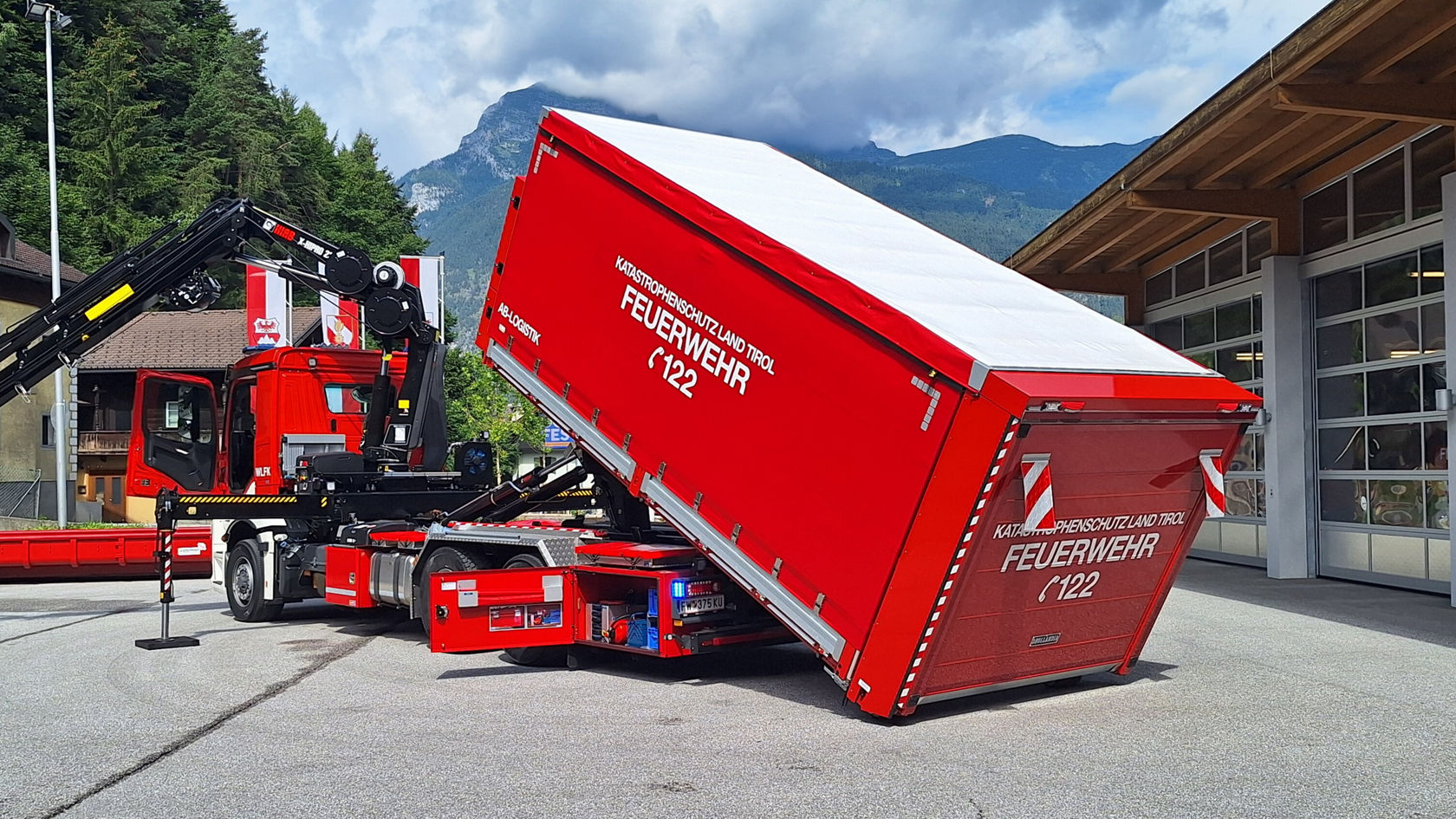 A red fire service truck sets down a container.