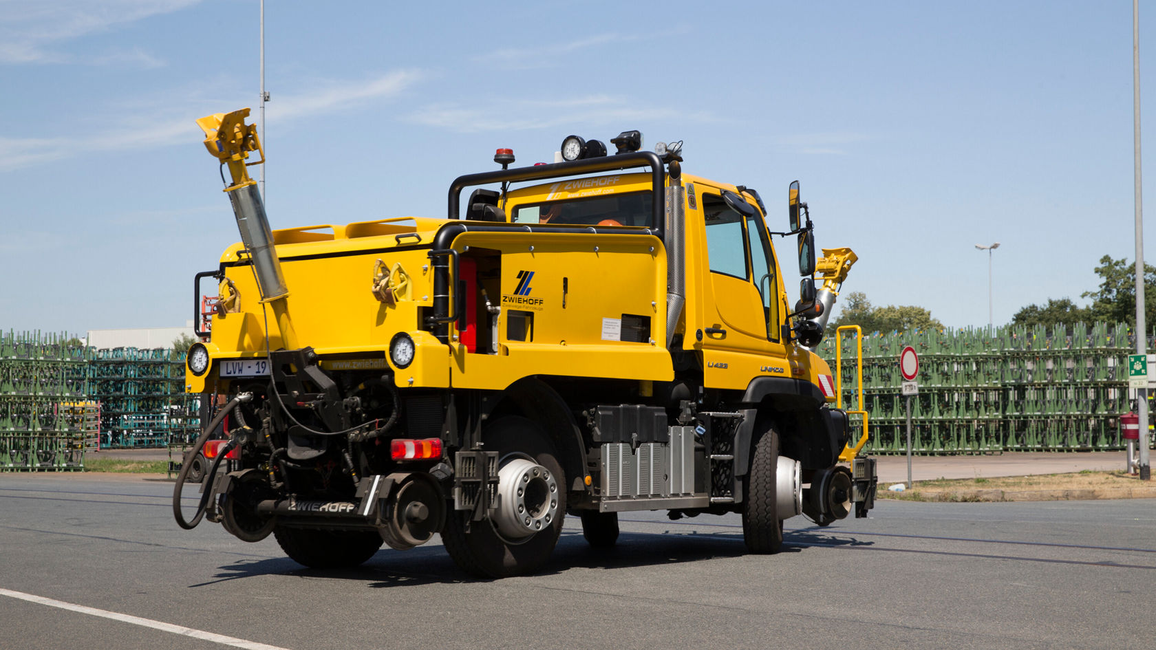 Ein gelber Mercedes-Benz Unimog-Truck steht auf einer Straße, versehen mit einem Arbeitsarm und einem Aufsatz zur Durchführung von Wartungsarbeiten.