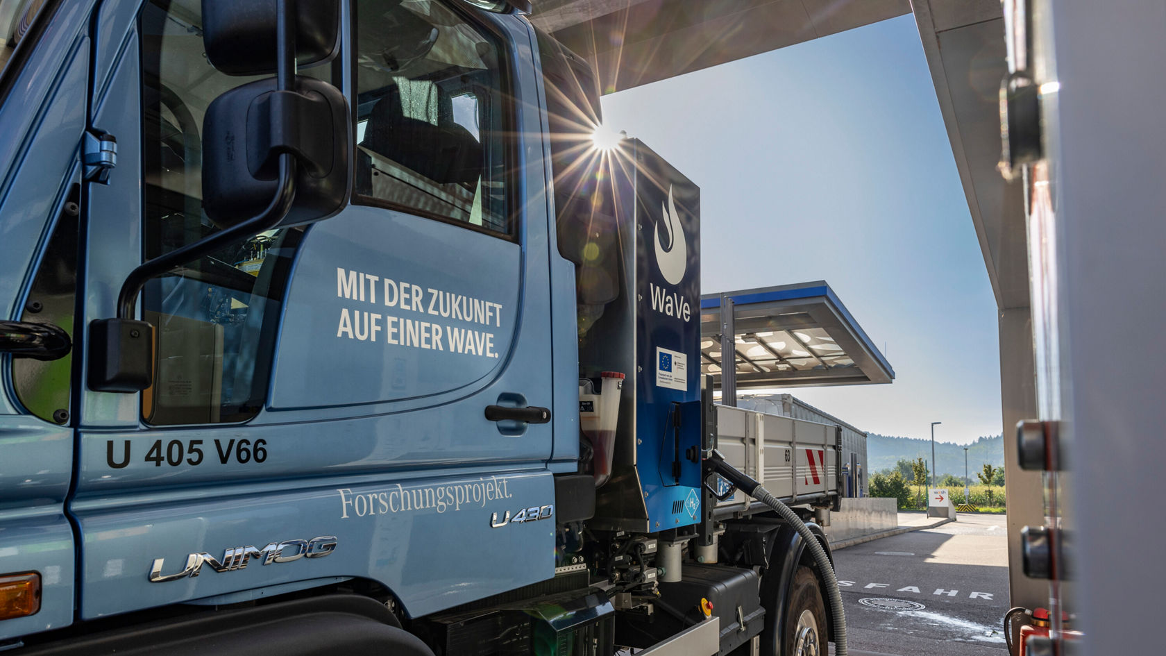 Ein blauer Mercedes-Benz Unimog steht auf einer Ausstellung. Er ist mit einem Aufbau ausgestattet, der für verschiedene Anwendungszwecke verwendet werden kann.