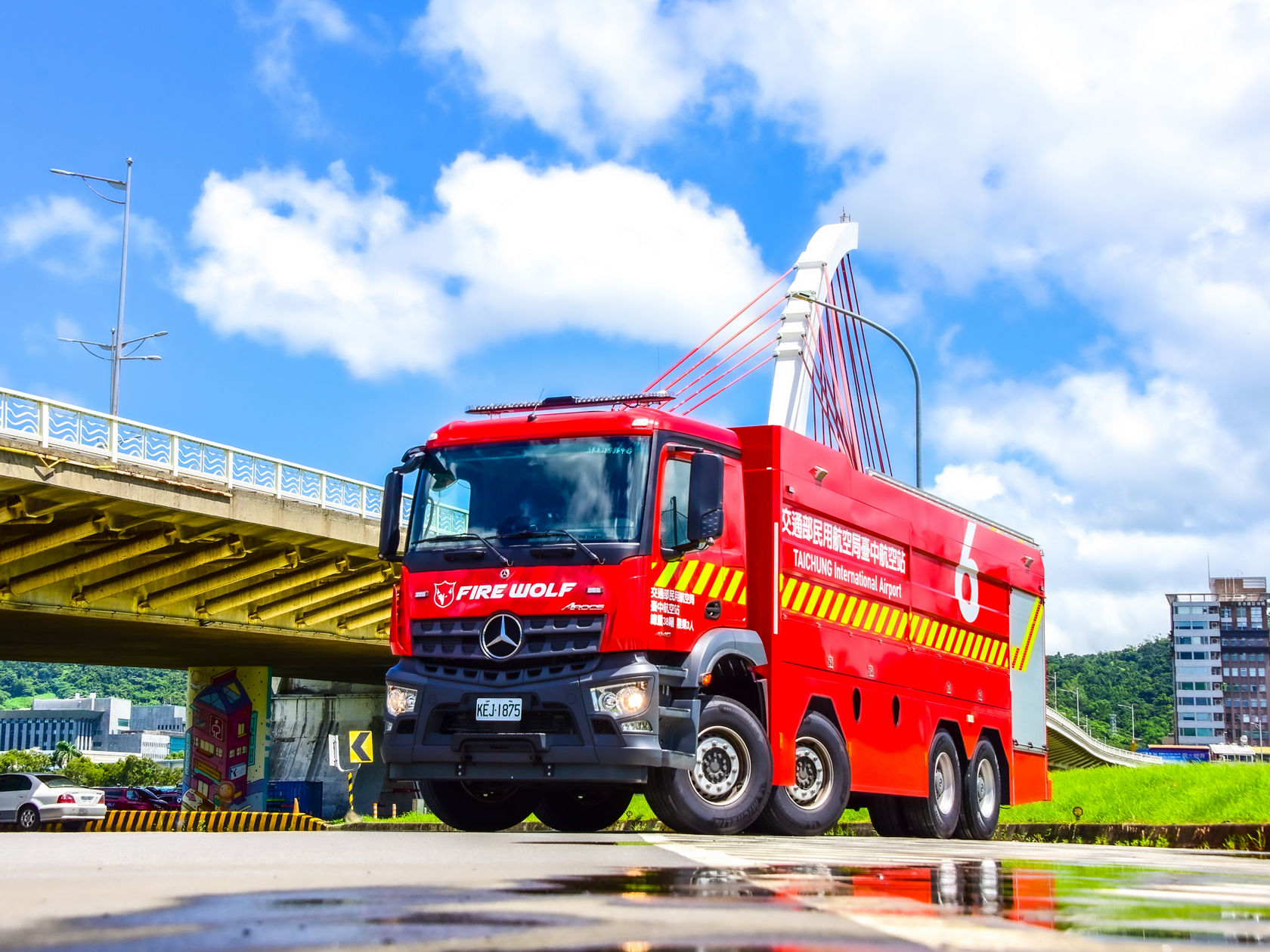 Ein rotes Mercedes-Benz Arocs Feuerwehrfahrzeug mit der Aufschrift „FIRE WOLF“ steht unter einer Brücke. 