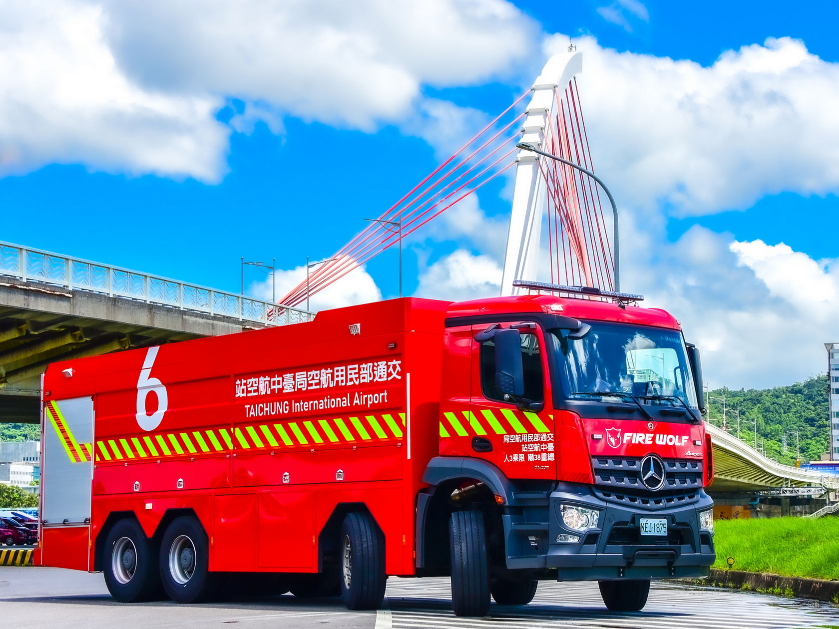 Ein rotes Mercedes-Benz Arocs Feuerwehrfahrzeug mit der Aufschrift „FIRE WOLF“ steht vor einer Brücke. 