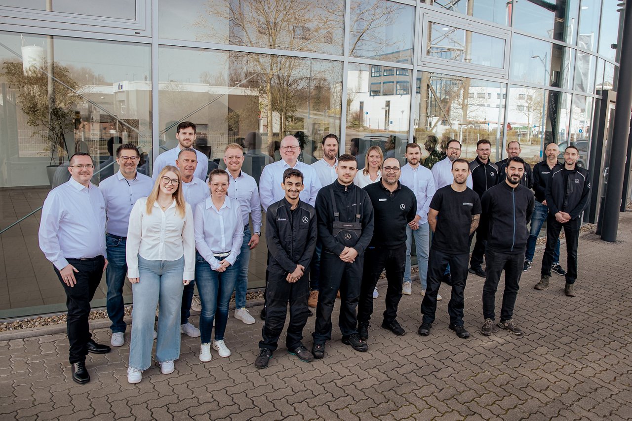 Das Bild zeigt eine Gruppe von Mitarbeitern vor einem Autohaus.