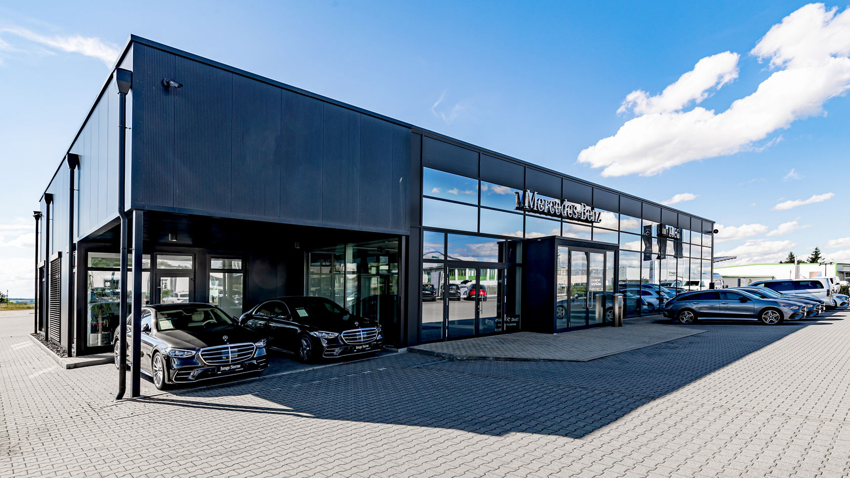 Autohaus Stollberg, große Glasfront, schwarze Fassade, Fahrzeuge vor dem Gebäude