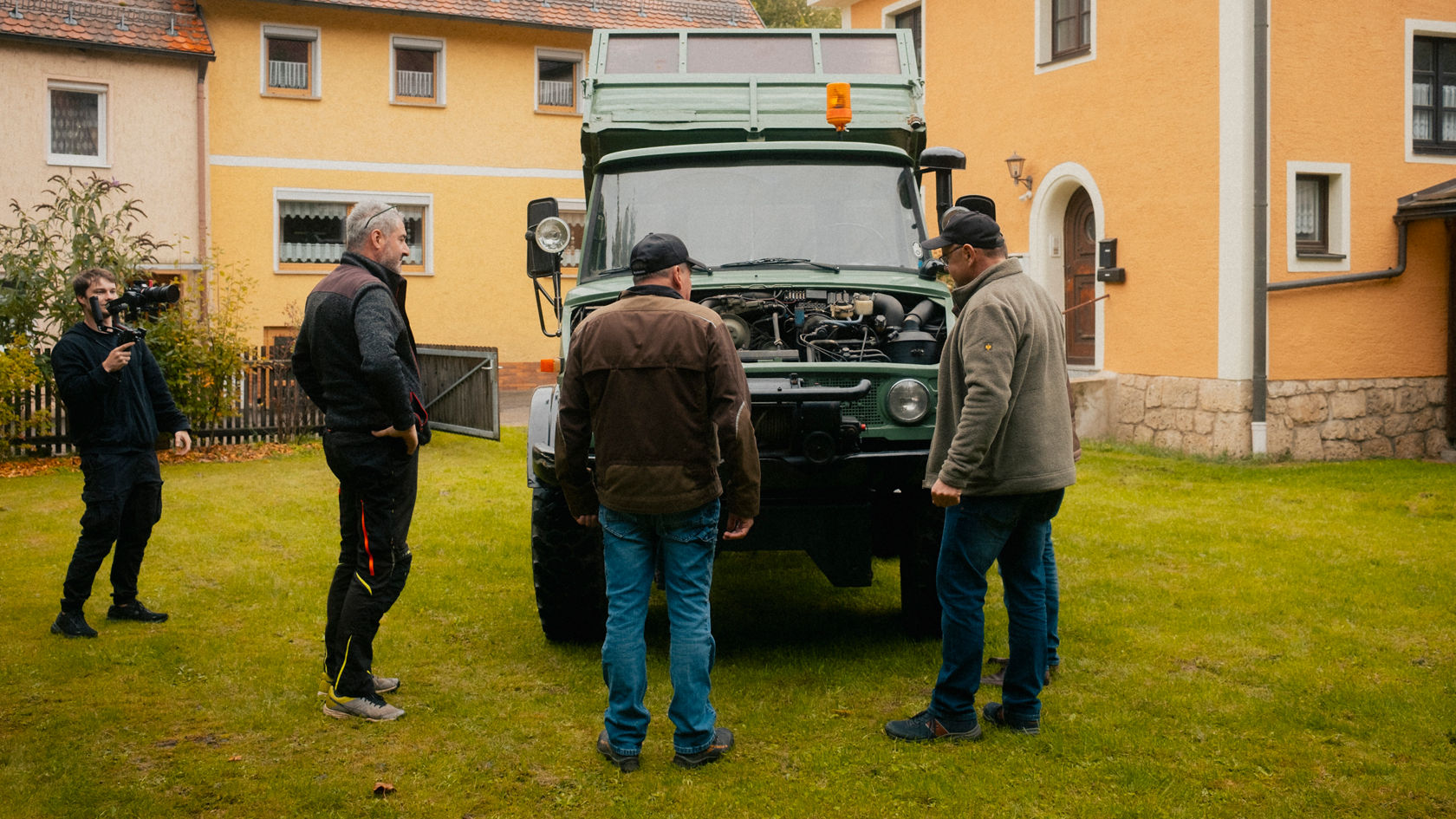 Vier personen staan voor een historische Unimog.