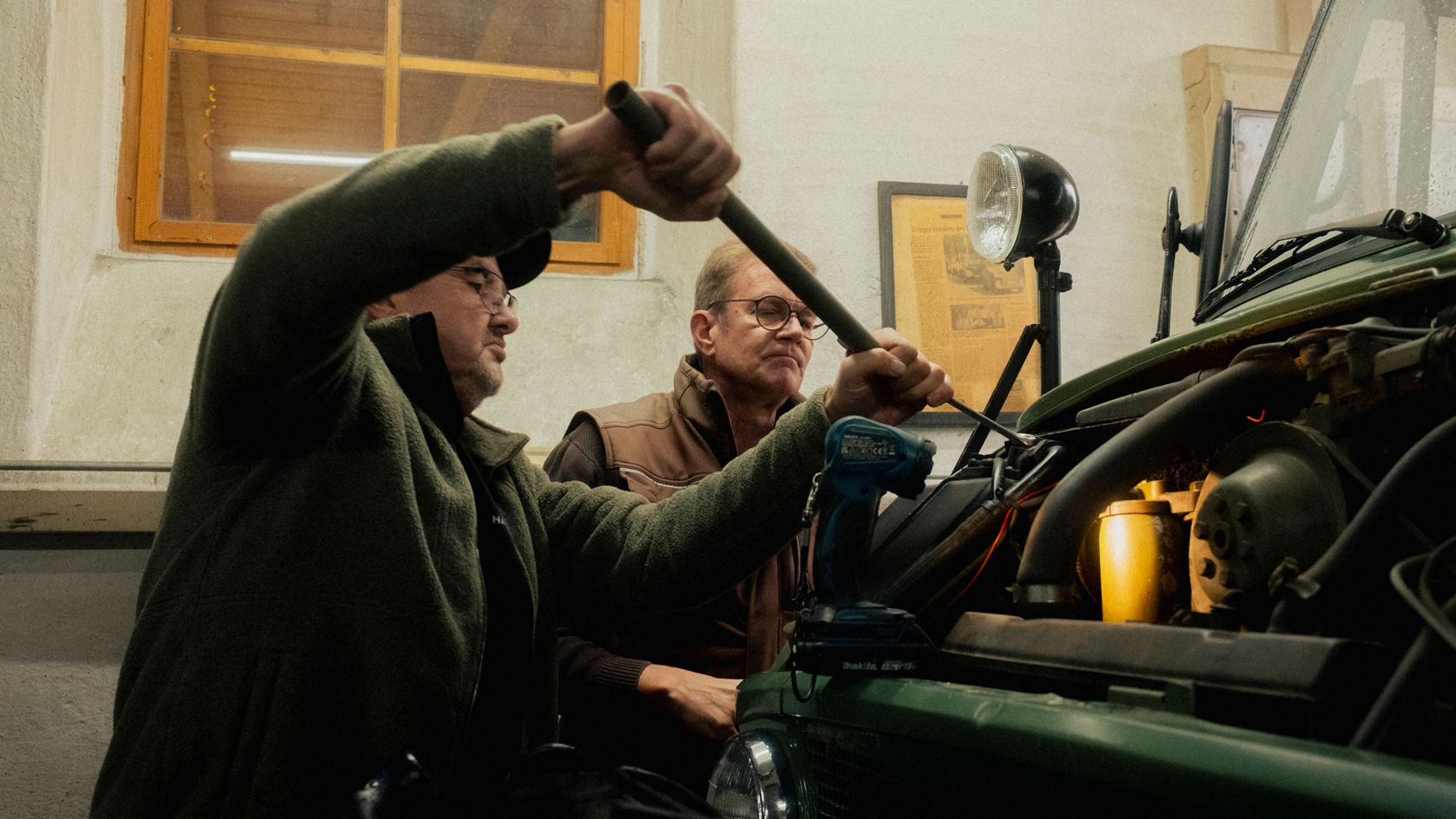 Zwei Personen schrauben an einem Unimog