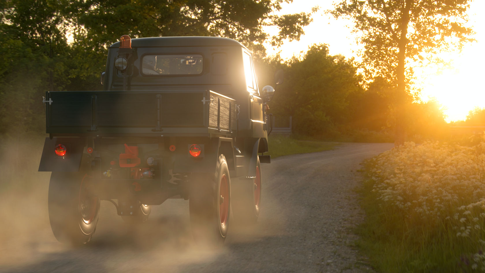 Een Mercedes-Benz Unimog rijdt op een smal, stoffig pad, terwijl de zon aan de horizon ondergaat en een warme lichtsfeer creëert.