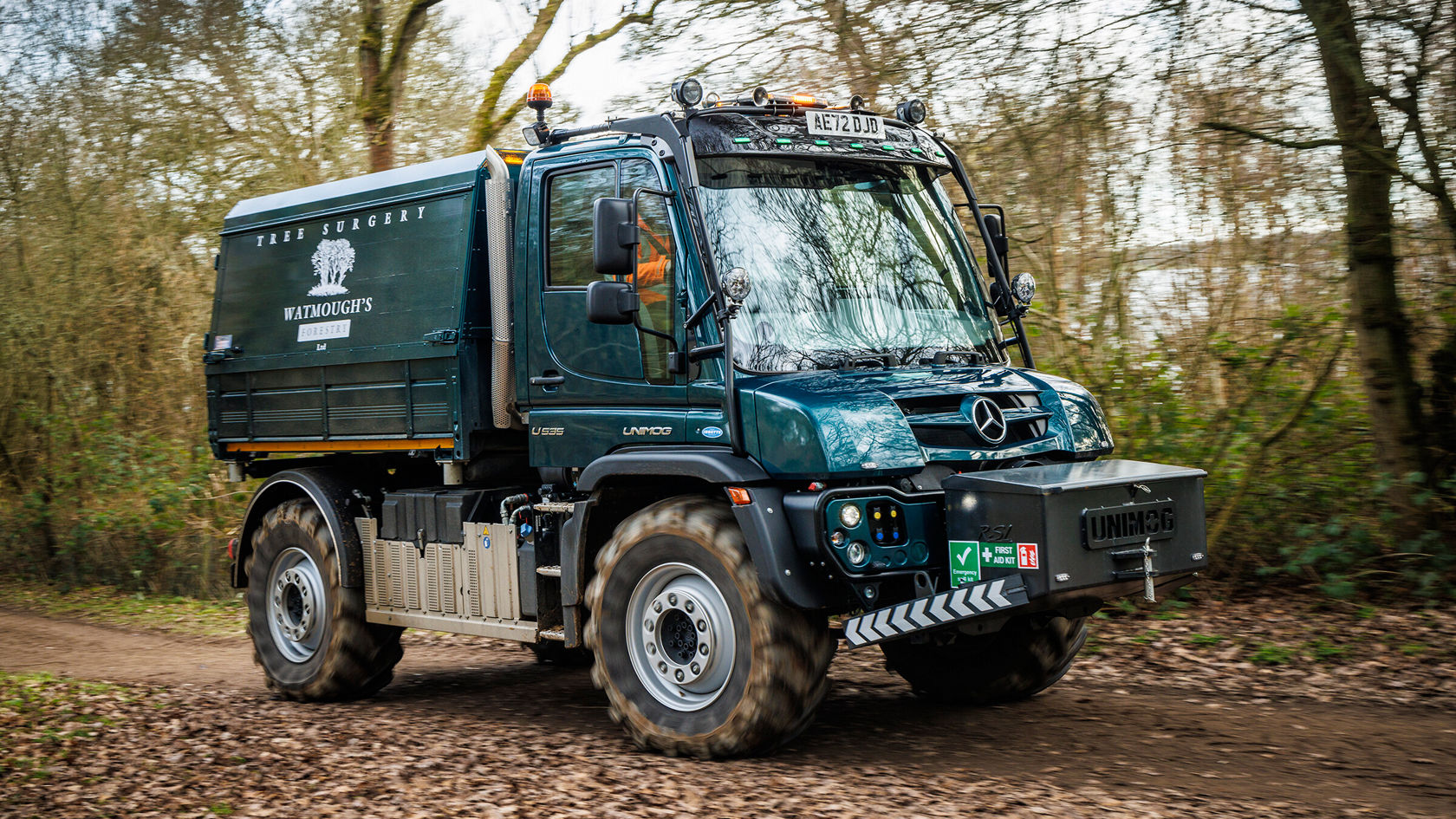 Ein grüner Mercedes-Benz Unimog U 535 fährt auf einem Waldweg.