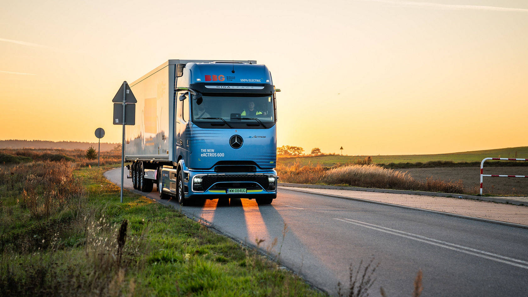 Ein blauer eActros 600 fährt bei Sonnenuntergang über die Landstraße.