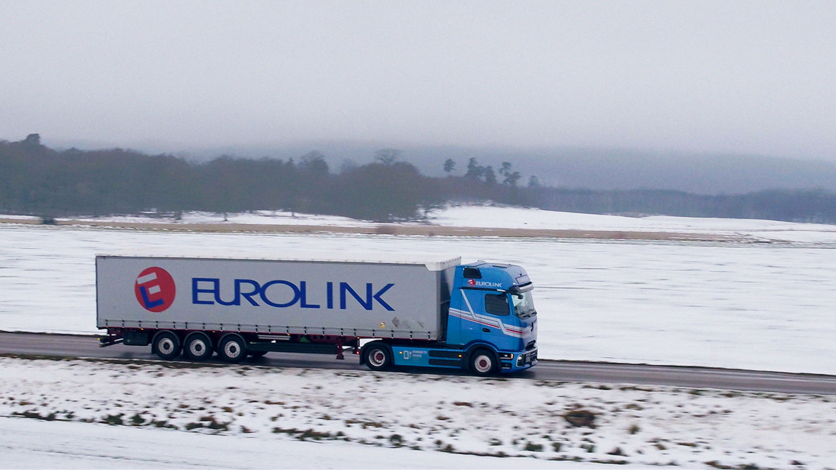 Ein blauer eActros 600 fährt über die verschneite Landstraße in Schweden.