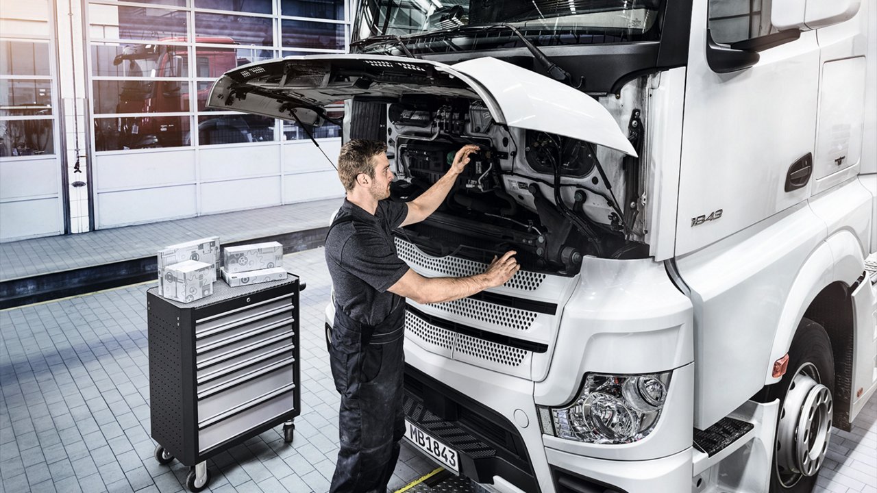 Op deze foto bekijkt een monteur de motor van een Mercedes-Benz Trucks.