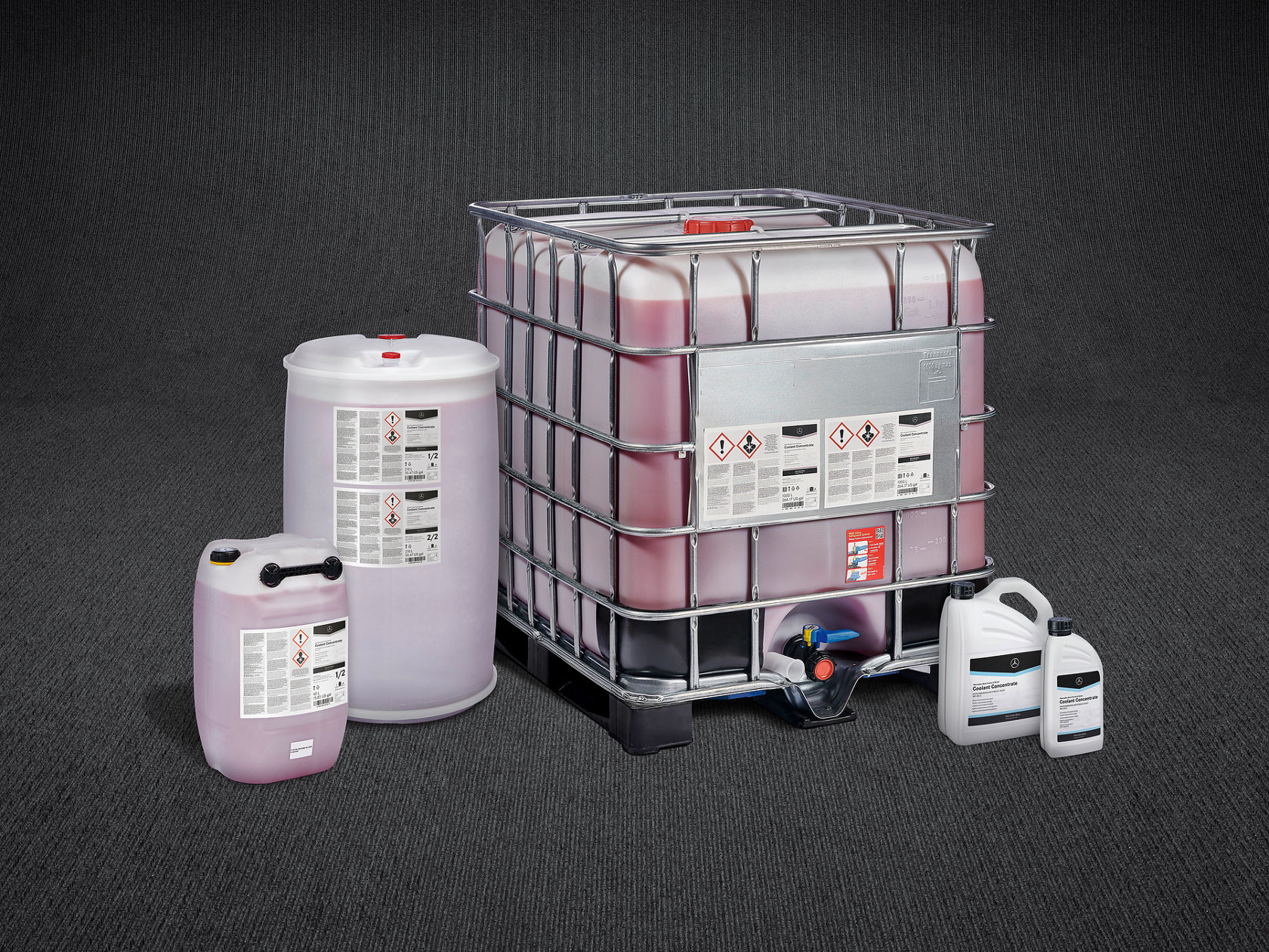 Verschiedene Behälter für Frostschutzmittel, darunter ein IBC-Container, ein Fass und kleinere Kanister, mit Mercedes-Benz Kennzeichnung vor einem weißen Hintergrund