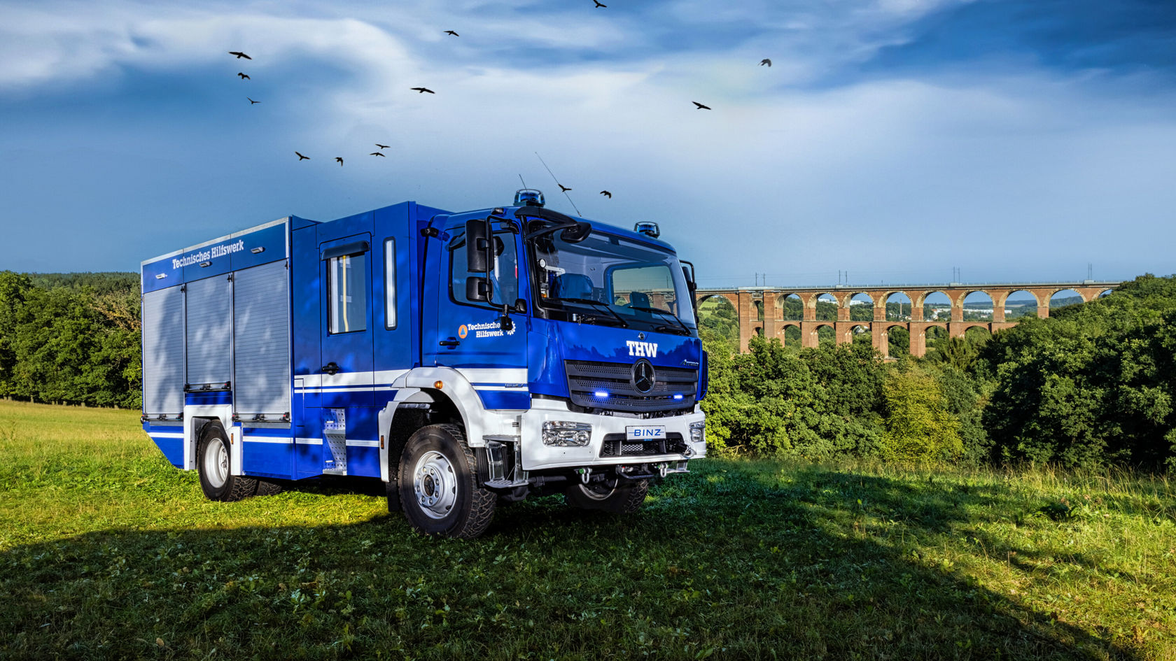 Un Atego Mercedes-Benz bleu se trouve sur une prairie.