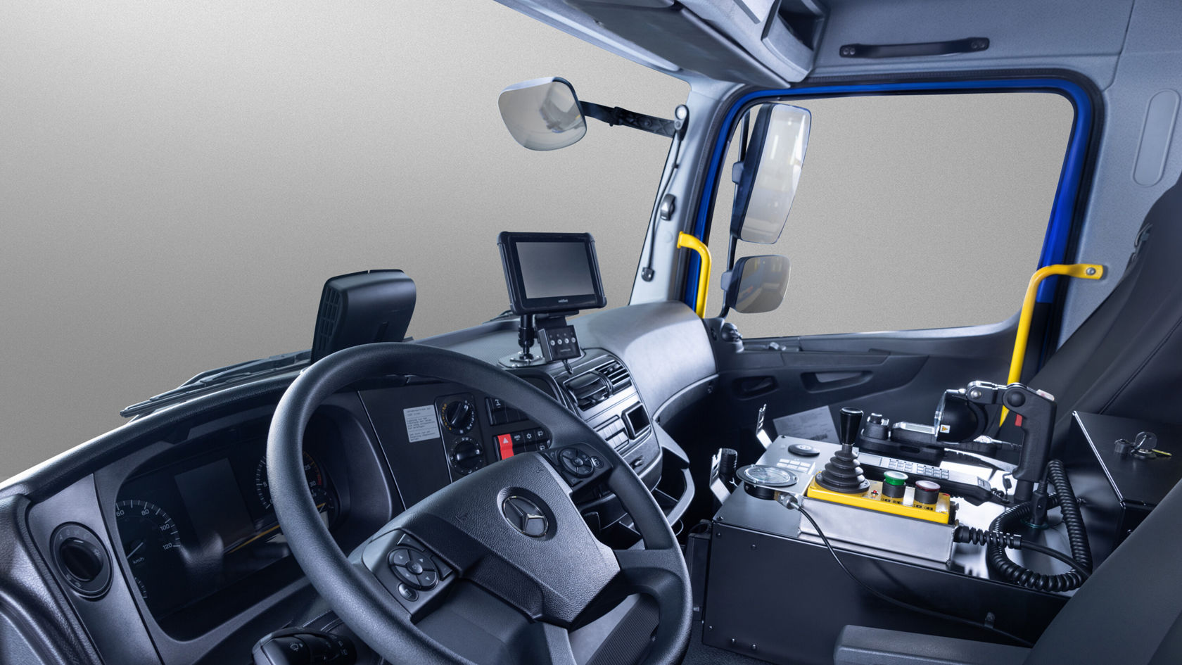 L'intérieur d'un Atego Mercedes‑Benz, avec un tableau de bord détaillé, un volant et un boîtier d'installation pour appareils techniques, est visible.