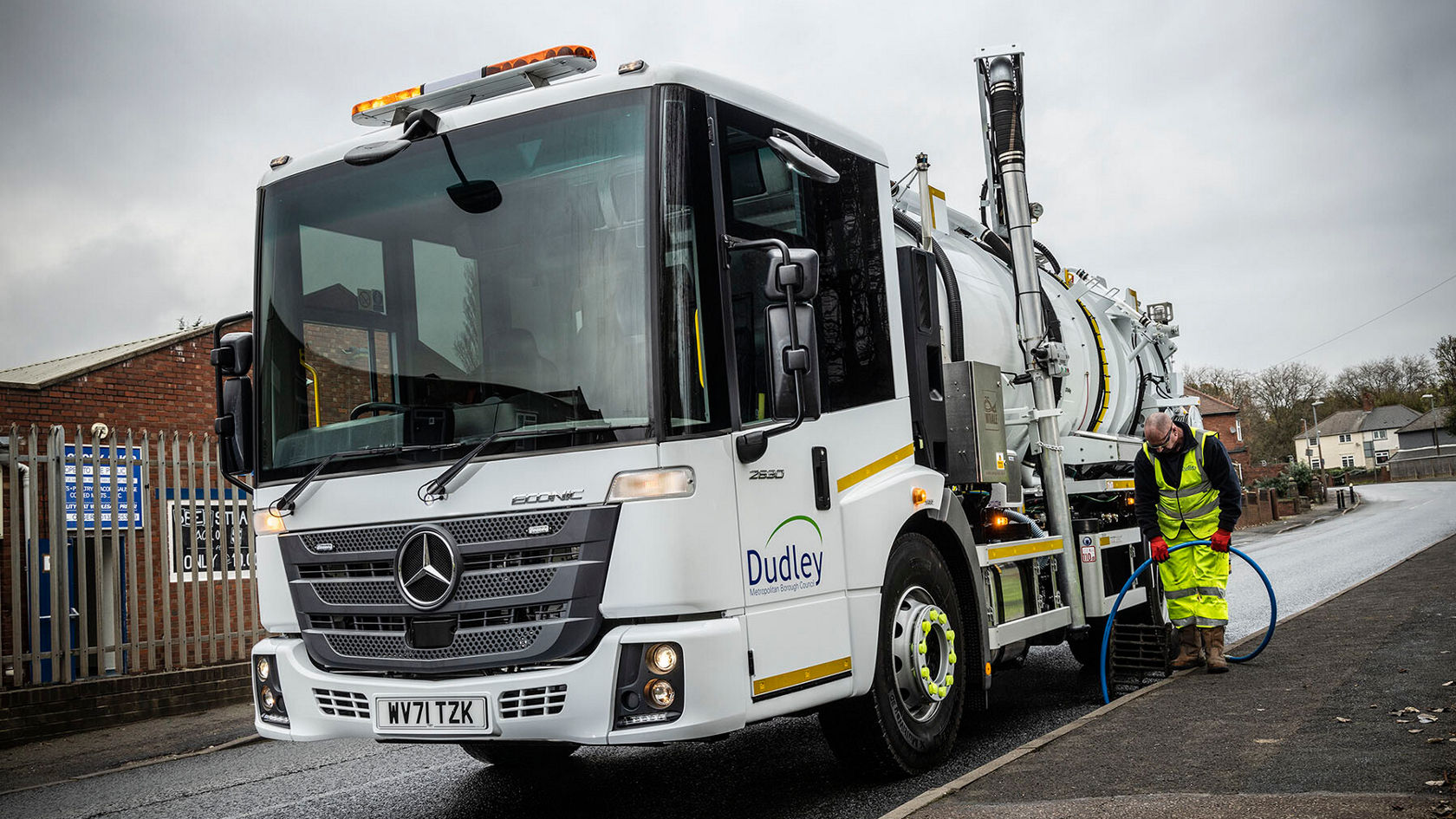 Ein Mercedes-Benz Econic steht auf einer Straße, während ein Arbeiter in reflektierender Kleidung ein Schlauchsystem bedient. Das Fahrzeug gehört zur Stadt Dudley.