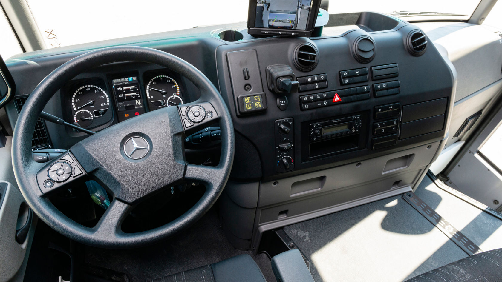 Puesto de conducción de un Mercedes-Benz Econic con volante, tablero de instrumentos, elementos de mando y equipo de navegación. El interior es funcional y está diseñado para las funciones de un camión.
