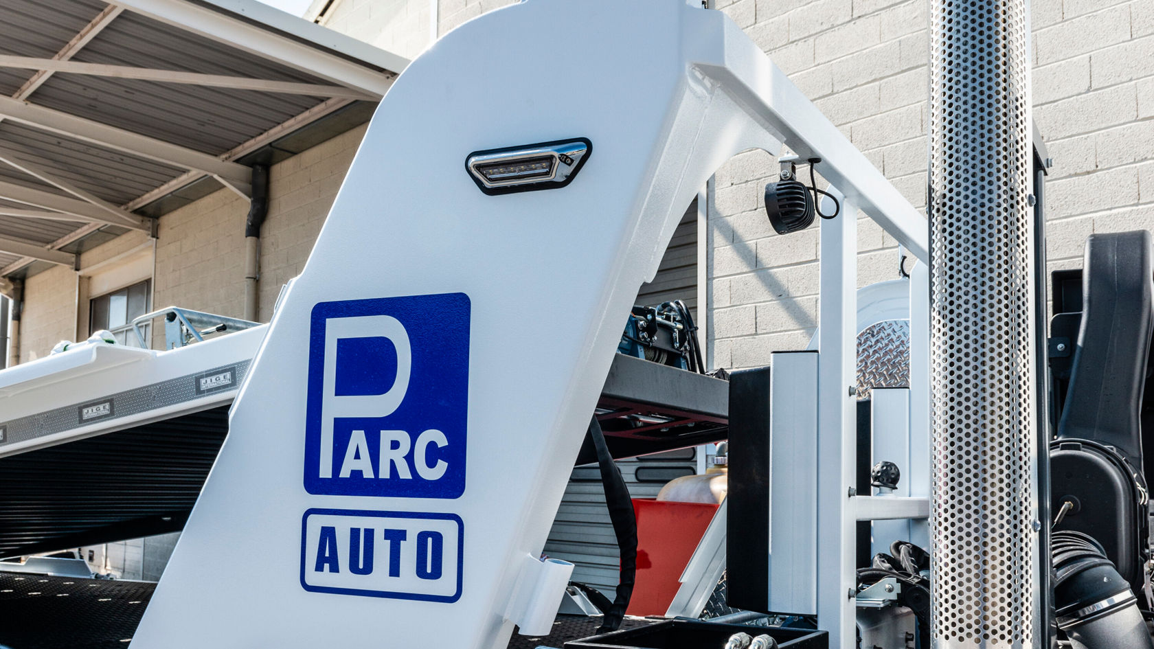 Un camión Mercedes-Benz Econic con un llamativo logotipo azul «PARC AUTO» en el revestimiento lateral y componentes del vehículo visibles, incluido el escape y la estructura del compartimento de carga.