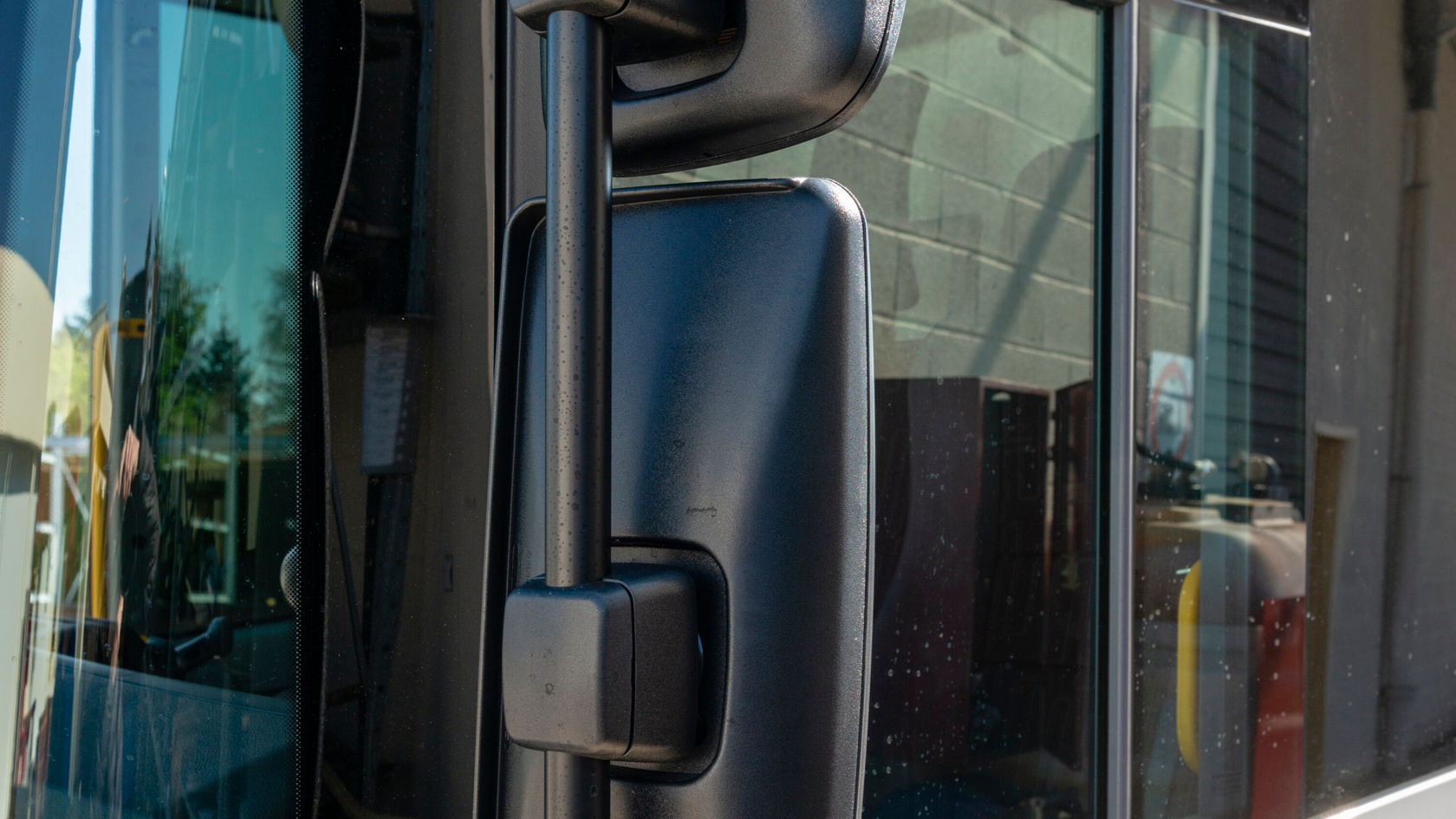 El espejo exterior de un Mercedes-Benz Econic muestra una superficie negra y está montado en la puerta del conductor. El número del vehículo es claramente visible.