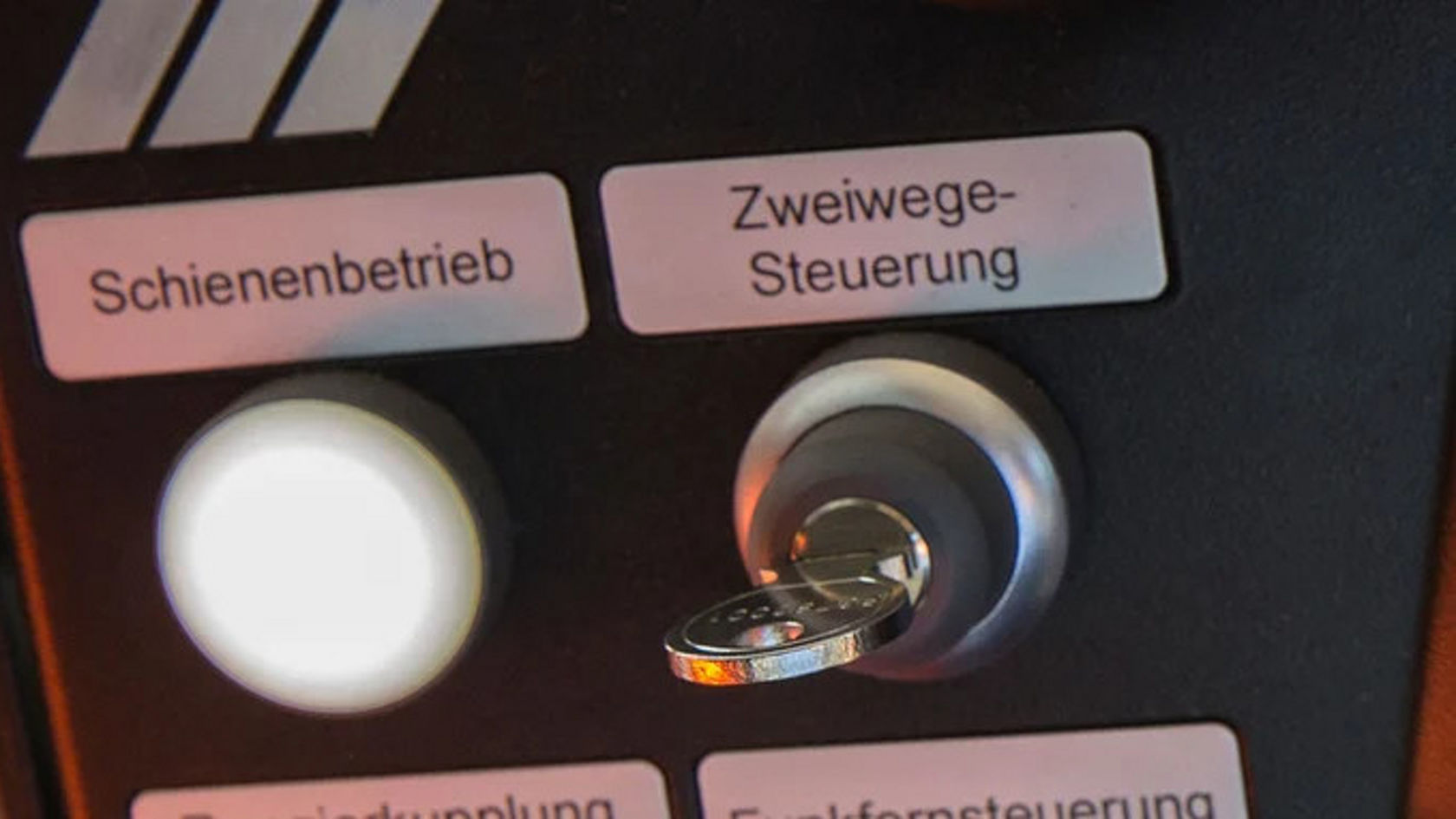Schaltfeld mit Tasten für "Schienenbetrieb" und "Zweiwege-Steuerung" sowie einem Schlüssel. Die Bedienung ist für spezielle Funktionen eines Fahrzeugs bestimmt.