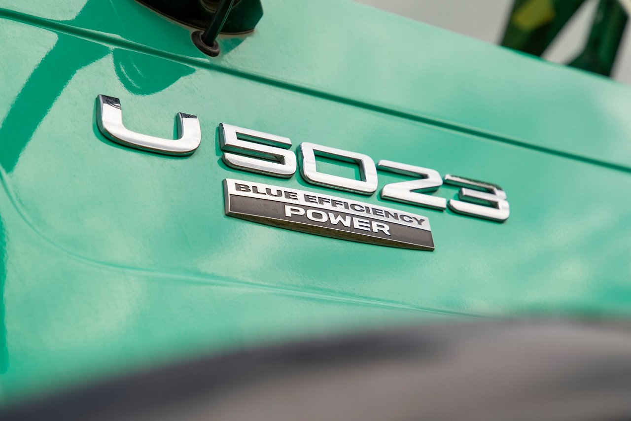 Mercedes-Benz U 5023 Logo mit der Aufschrift "BLUE EFFICIENCY POWER" auf einer grünen Oberfläche, betont die Effizienz und Leistung des Fahrzeugs.