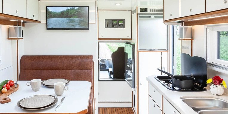 Interior of a motorhome with a dining table and a kitchen.
