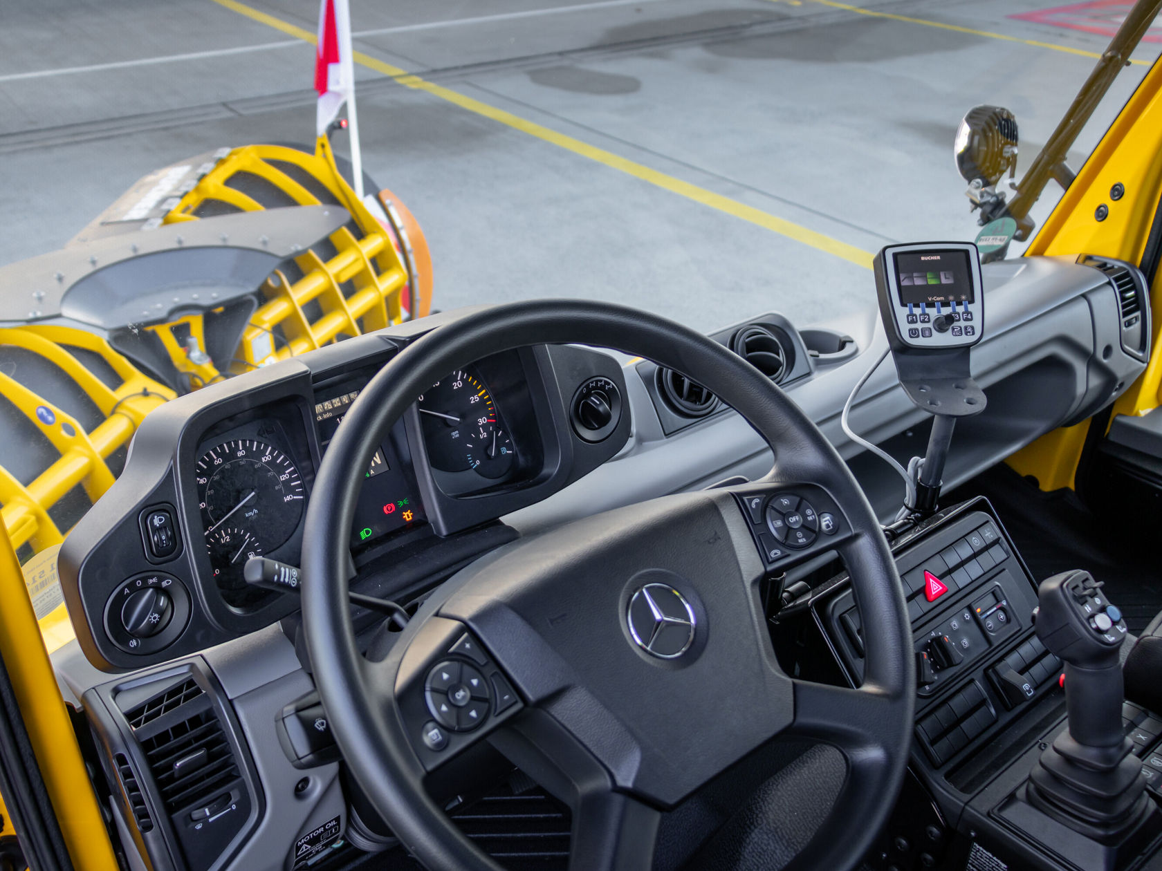 Cockpitansicht eines Mercedes-Benz Fahrzeugs mit Lenkrad, Armaturenbrett und modernen Bedienelementen, ideal für den Einsatz im Straßenbau oder Räumungsarbeiten.