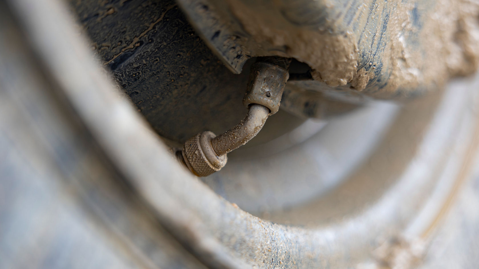 Gros plan d'une roue boueuse montrant une valve.