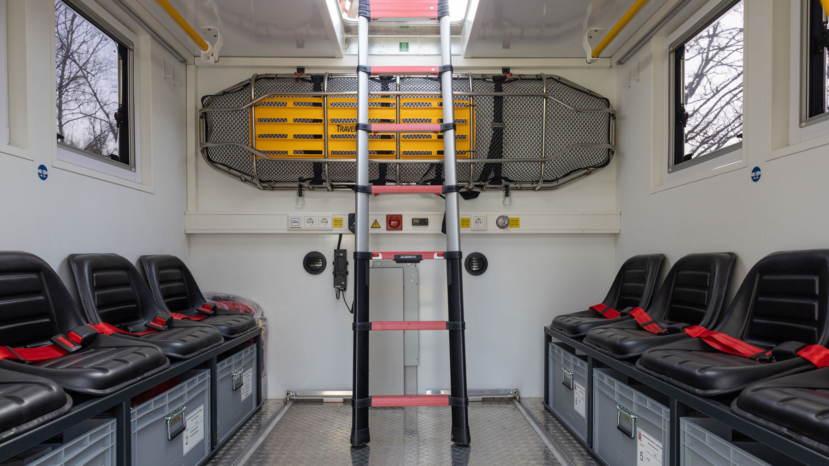 Habitacle d’un véhicule avec plusieurs places assises, une échelle et une cloison porte-brancard pouvant être utilisée pour des interventions d’urgence ou de sauvetage.