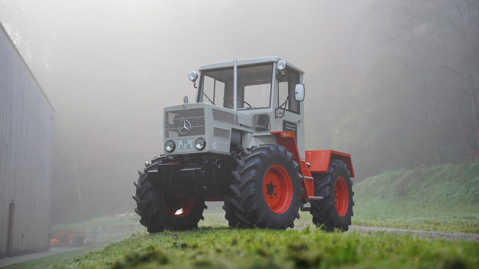 Ein Mercedes-Benz Unimog steht auf einer grünen Wiese. Die Umgebung ist von Nebel umgeben, was eine ruhige Atmosphäre schafft.