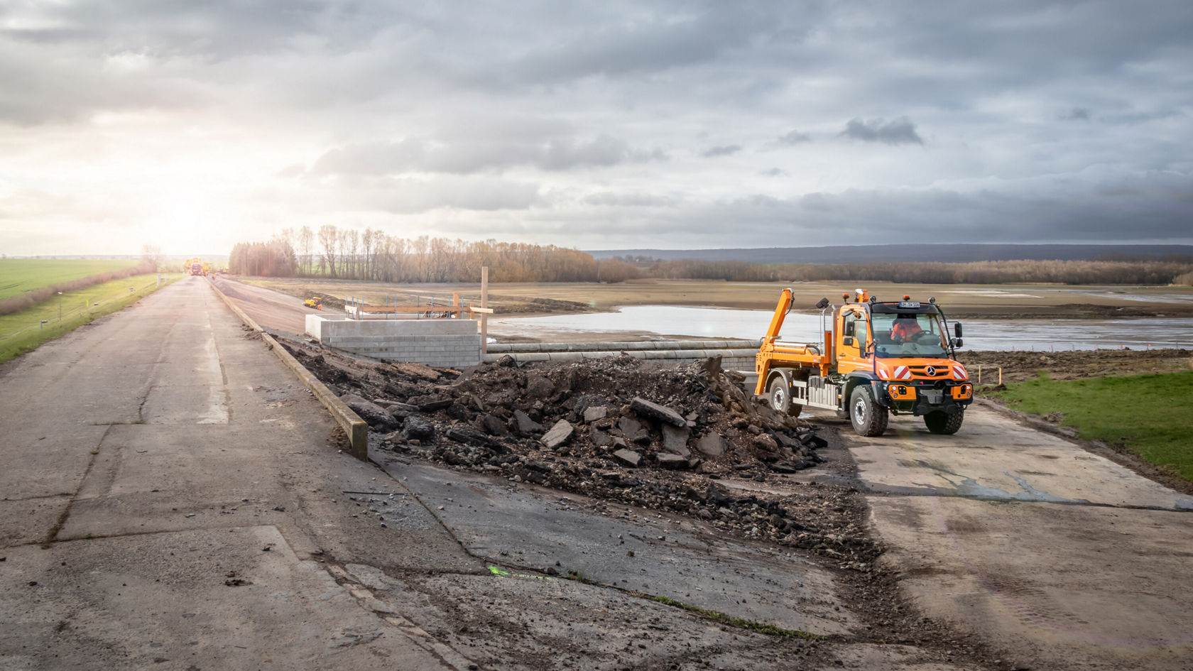 Un Unimog U 530 sur un chantier à côté d'une voie publique.