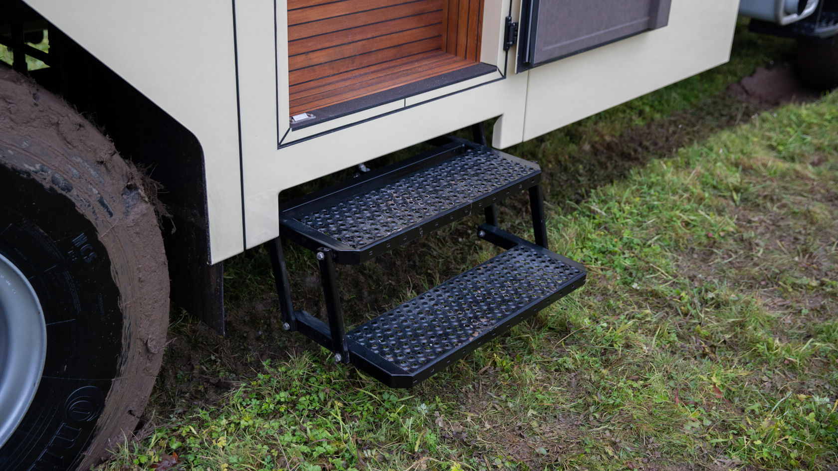 Schwarze Außentreppen mit zwei Stufen, die an einem Zetros Wohnmobil montiert sind. Die Treppe hat eine rutschfeste Oberfläche für besseren Halt.