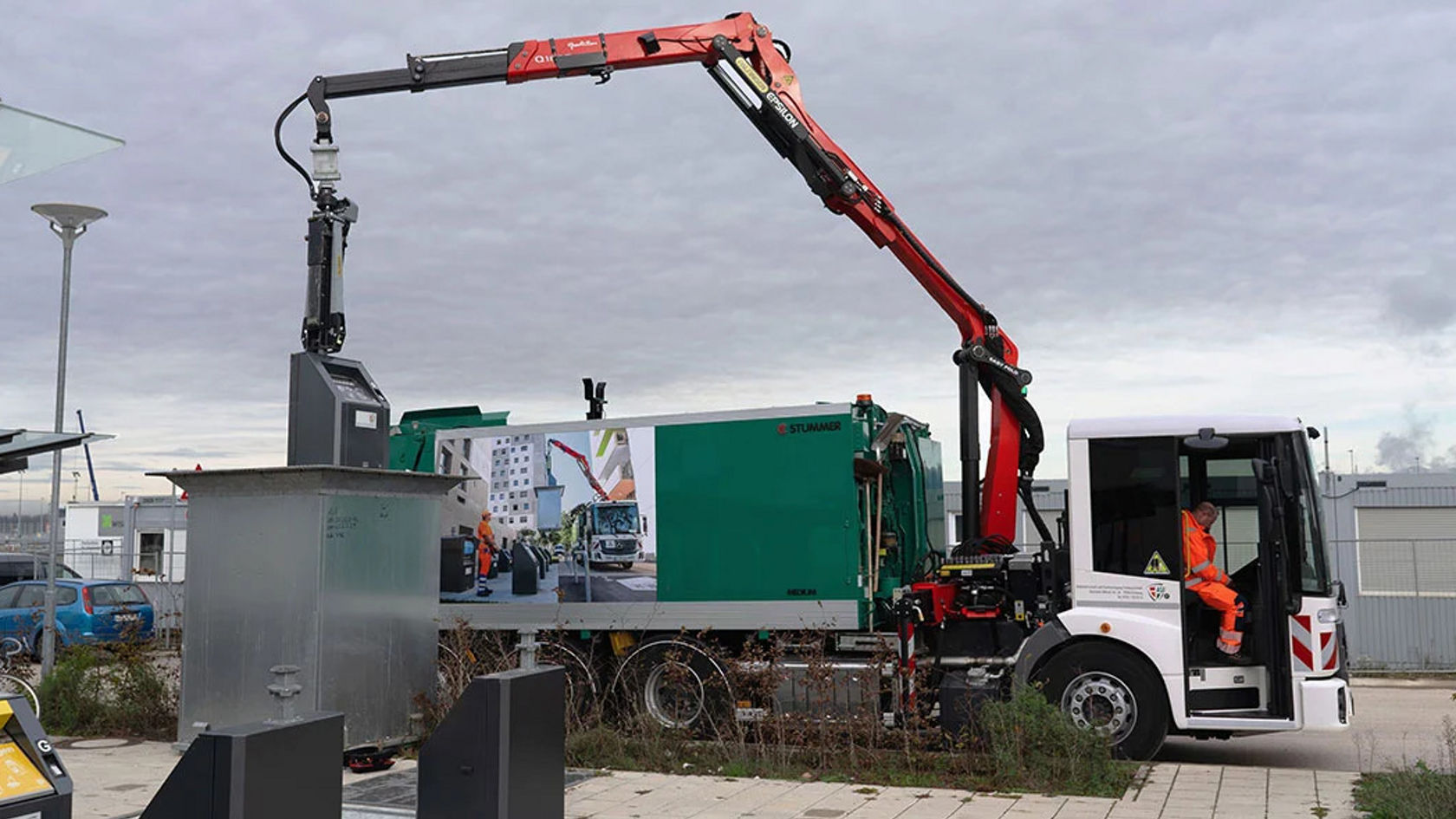 An Econic refuse truck with a crane arm lifts a waste container.