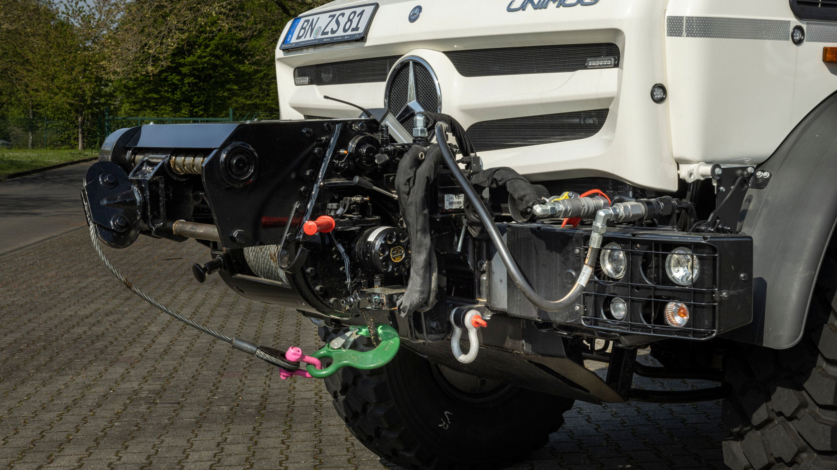 Close-up of the front of a Mercedes-Benz Unimog showing the drive system and technical components, ideal for versatile off-road and agricultural applications.