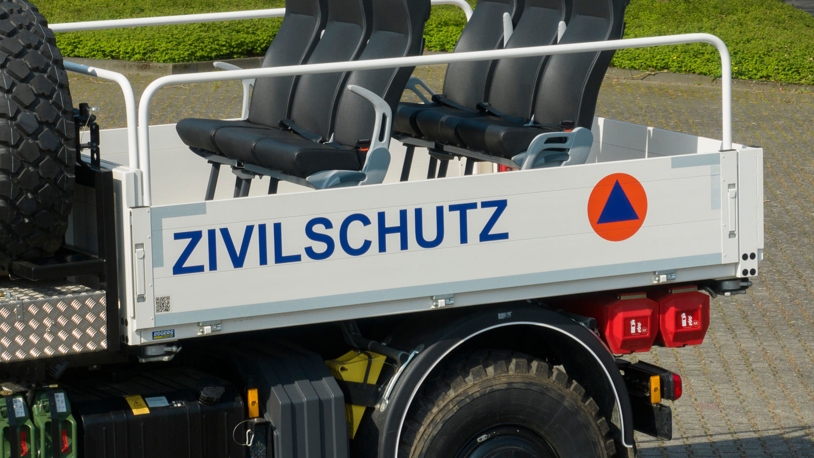 Four black seats on a vehicle transport area with the inscription "CIVIL PROTECTION" and an orange symbol. Ideal for civil protection.