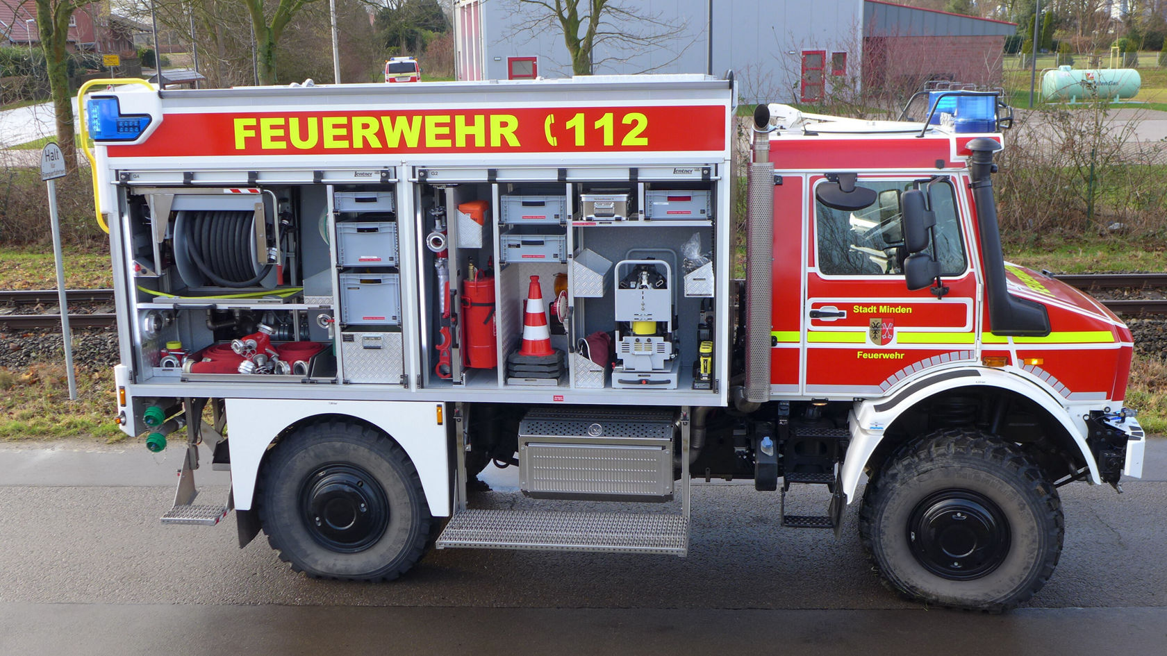 Un véhicule de pompiers Mercedes-Benz, peint en rouge et portant l'inscription « POMPIERS 112 », présente une vaste gamme d'appareils et d'équipements de lutte contre l'incendie.
