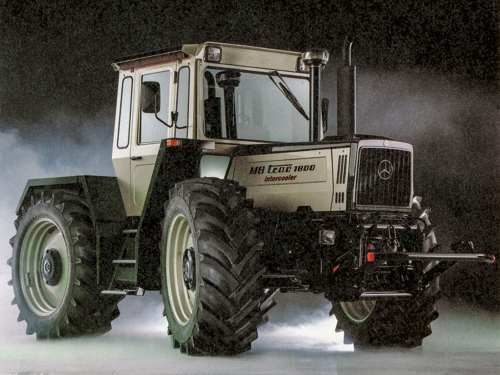 Der Unimog von Mercedes-Benz steht in einer rauchigen Umgebung, zeigt seine robusten Reifen und bemerkenswerte Bauweise, ideal für landwirtschaftliche und anspruchsvolle Einsatzgebiete.