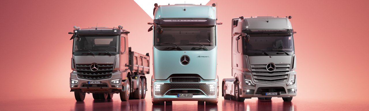 Drei verschiedene Mercedes-Benz Lkw-Modelle stehen nebeneinander auf nassem Asphalt.