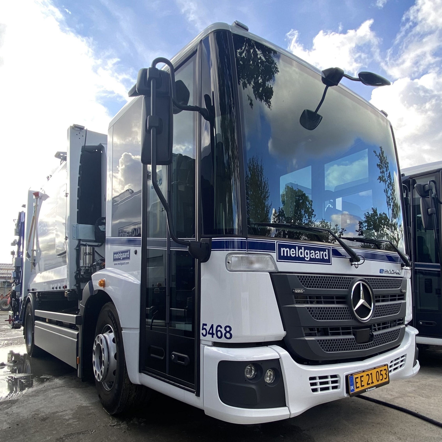 Econic von Mercedes-Benz, ein moderner Müllwagen, steht auf einer nassen Fläche. Der LKW ist mit einem Logo und einer Nummer gekennzeichnet.