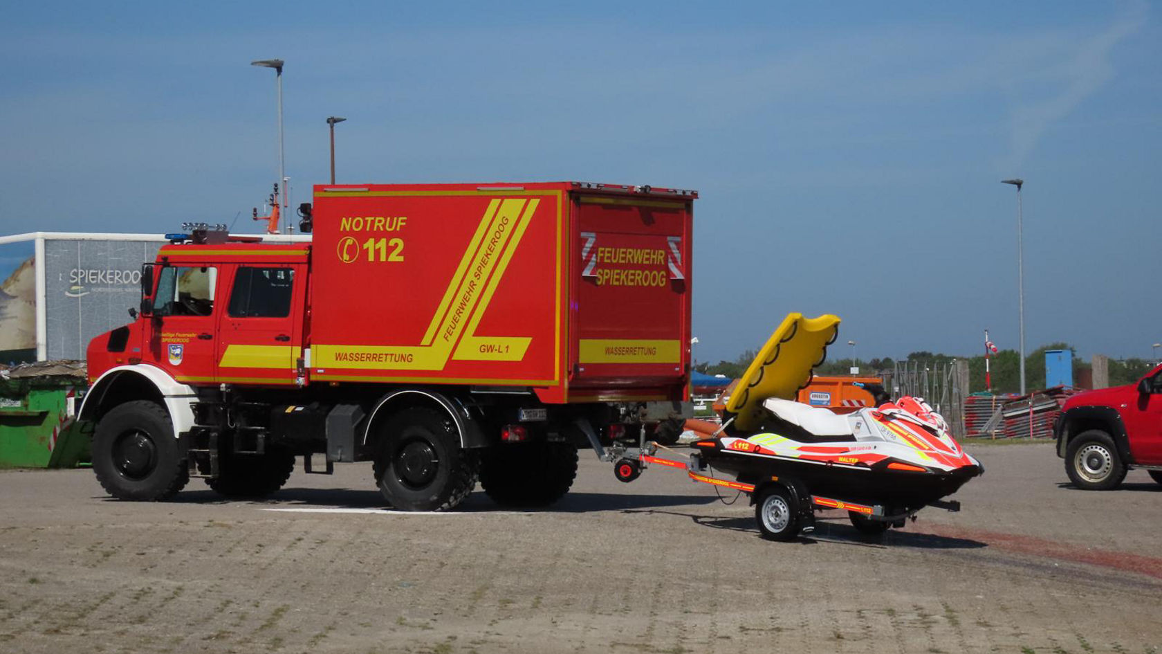 Unimog von der Seite zieht einen Anhänger mit motorisiertem Wasserrettungsfahrzeug