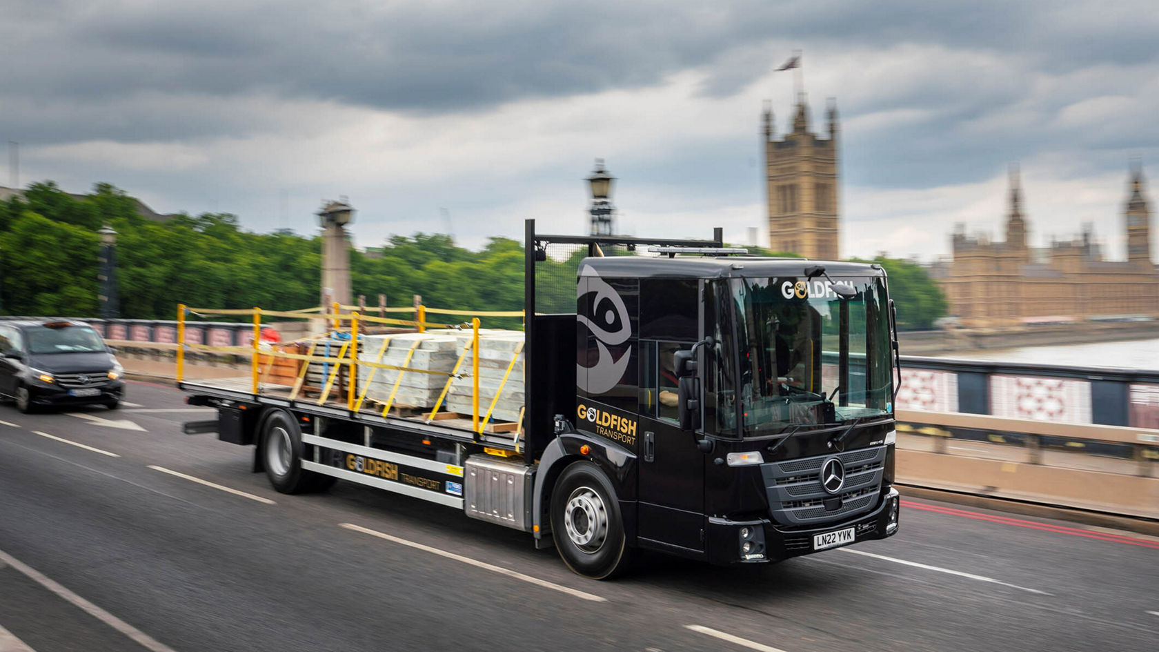 Ein Mercedes-Benz Econic fährt mit Baustellenmaterial auf einer Straße in der Nähe des Parlamentsgebäudes in London.