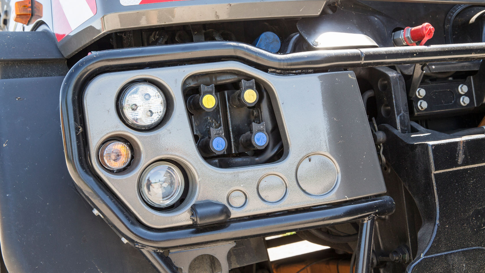 Steuerpanel eines Mercedes-Benz Lkw mit mehreren Bedienelementen und Anzeigen, darunter Scheinwerfer- und Blinkerleuchten in verschiedenen Farben.