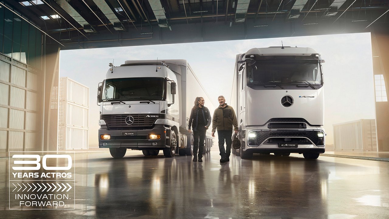 Zwei Actros Lkw, alt und neu, mit zwei Personen in einer Halle.