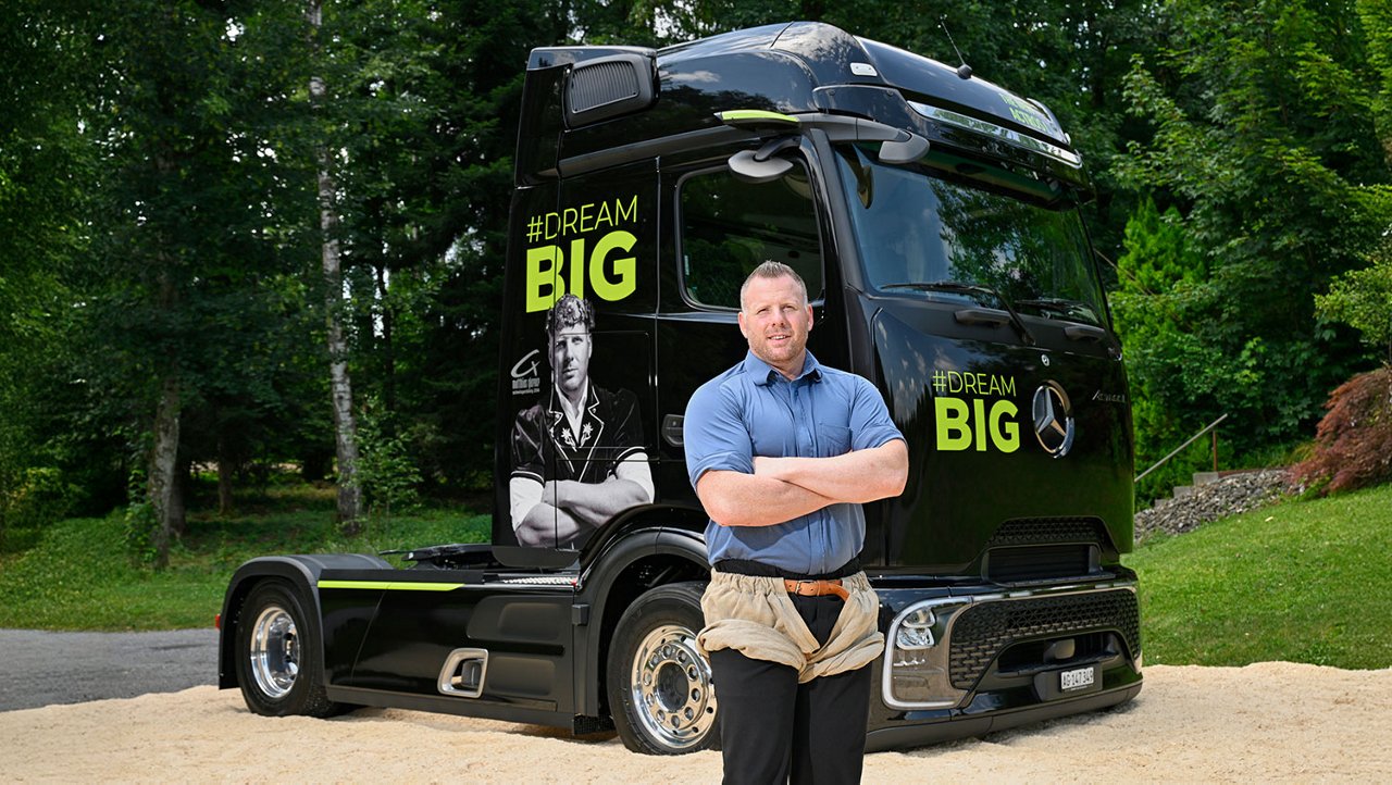 Matthias Glarner se tient devant un camion Mercedes noir avec l’inscription « #DreamBig » et son portrait.