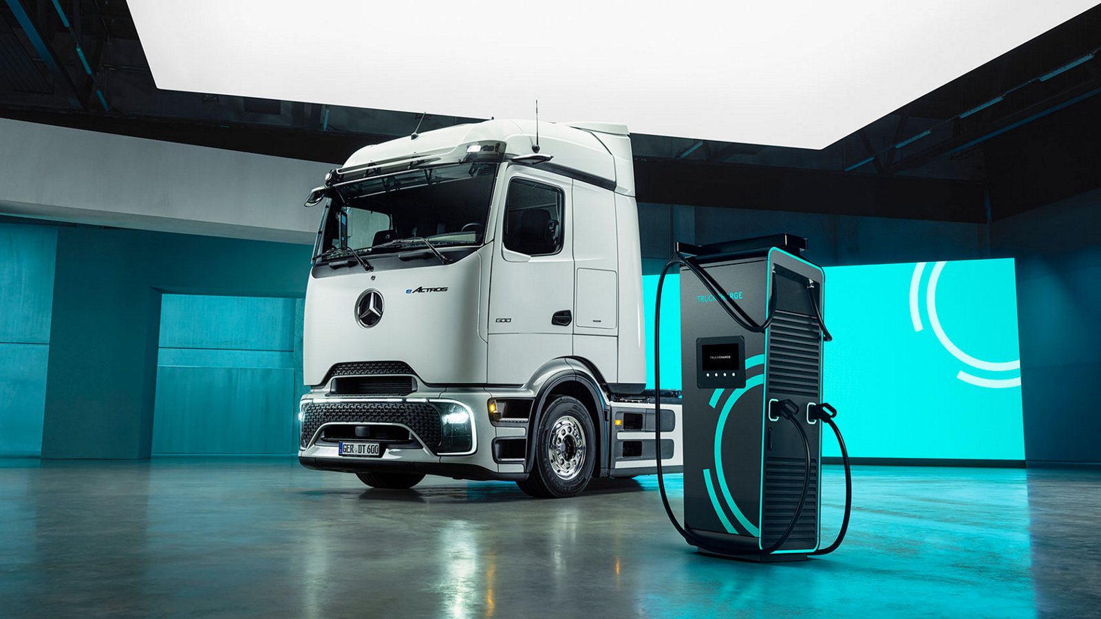 Camion électrique Mercedes-Benz eActros 600 à côté d'une borne de recharge rapide dans un espace moderne